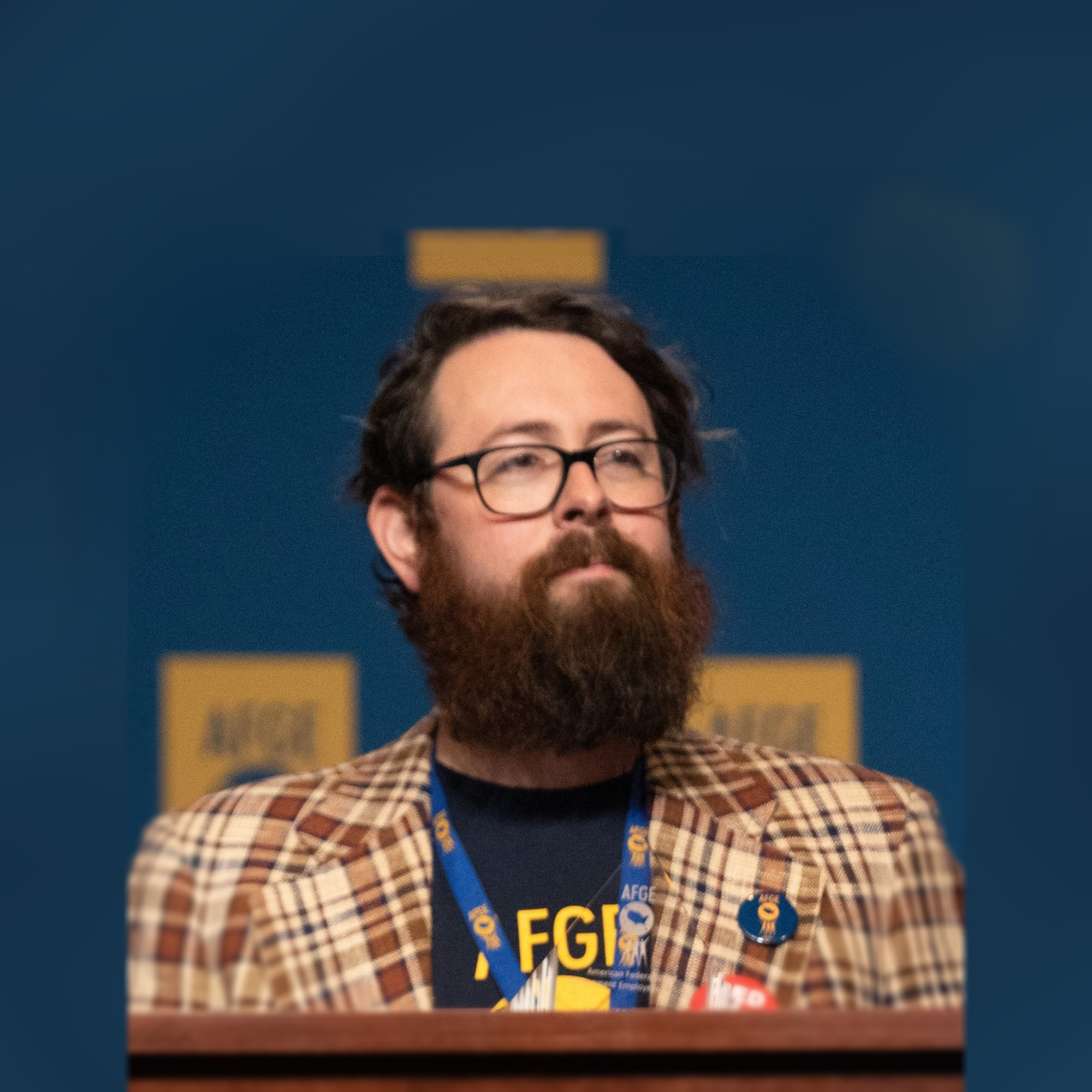 Photo of Matt Muchowski standing at a podium with a blue background